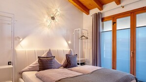 Ein Schlafzimmer mit Bett, Nachttischen, einer Hängelampe, einem Kleiderschrank und einem Fenster mit Vorhängen.