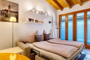 Een slaapkamer met een bed, nachtkastje, lamp en een stadsbeeld.