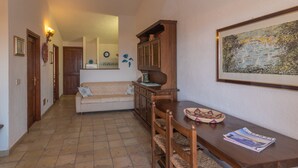 Un pasillo con un aparador de madera, una mesa de comedor con sillas, un sofá y un cuadro en la pared.