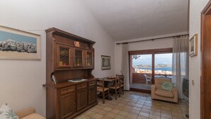 Una sala de estar con un aparador de madera, una mesa de comedor, un sofá y vistas a través de un ventanal.