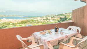 Un balcón con una mesa para dos, con vista a un pueblo costero.