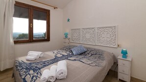 A bedroom with a bed, a nightstand, a window, and a decorative wall panel.