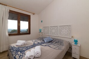 A bedroom with a bed, a nightstand, a window, and a decorative wall panel.