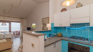 A kitchen with a gas stove, oven, and blue tiled backsplash.