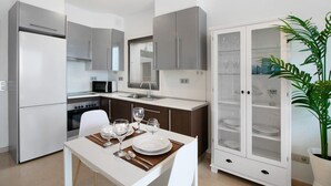 Una cucina moderna con zona pranzo, elettrodomestici in acciaio inossidabile e un armadietto con ante in vetro.