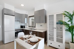 Une cuisine moderne avec un coin repas, des appareils en acier inoxydable et un meuble avec des portes en verre.
