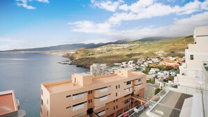 Paesaggio costiero con edifici che si affacciano sul mare, caratterizzato da balconi e un cielo sereno.