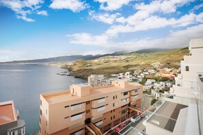 Un paysage urbain côtier avec des bâtiments donnant sur la mer, agrémenté de balcons et d’un ciel dégagé.
