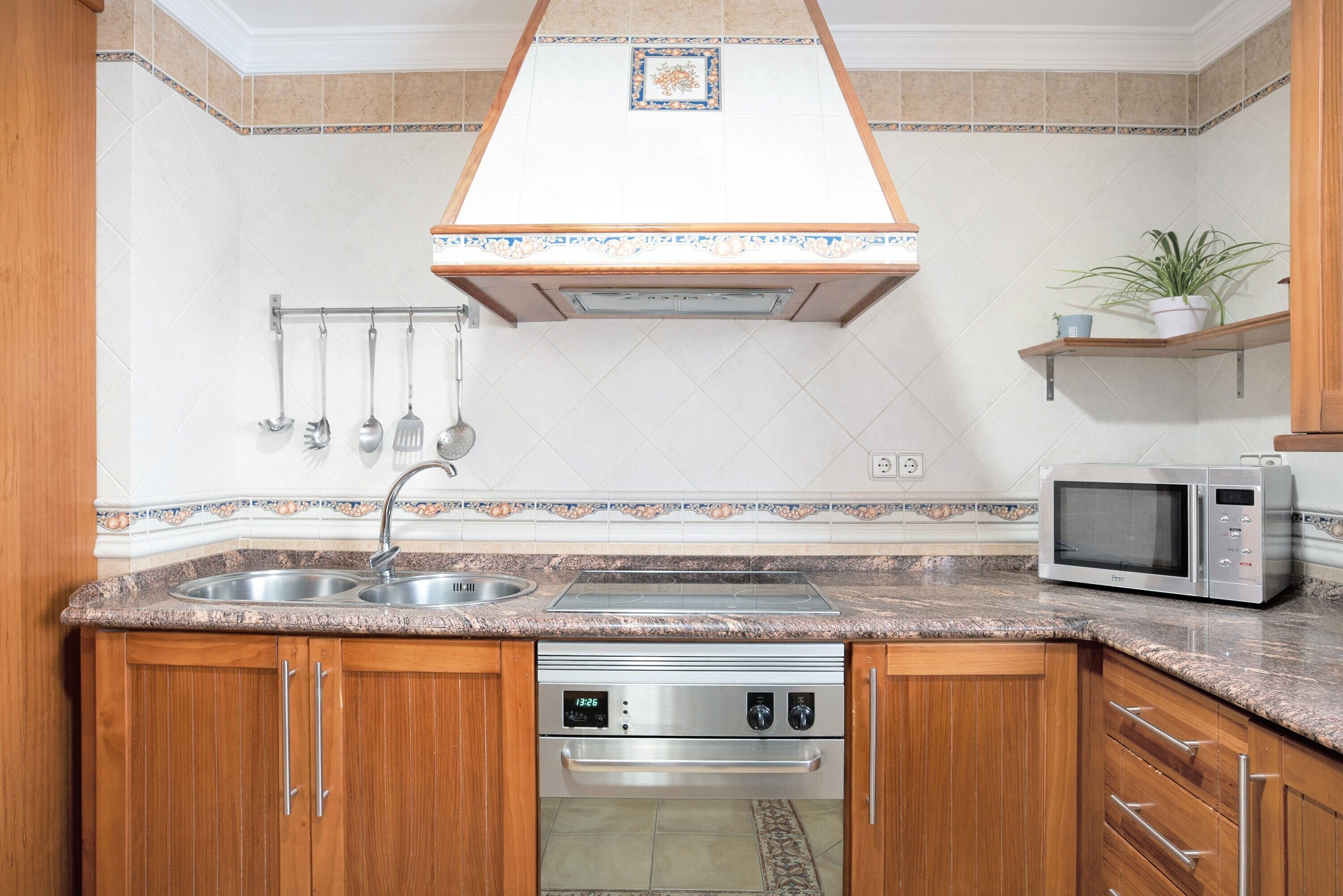 A kitchen with wooden cabinets, a stainless steel sink, a microwave, and a built-in oven.