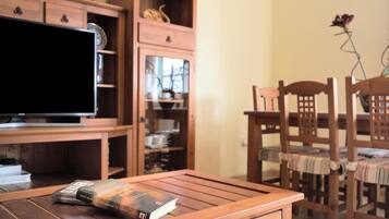 Una mesa de madera con un libro, un televisor y un mueble de madera con estantes.