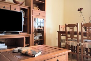 A wooden table with a book, a television, and a wooden cabinet with shelves.