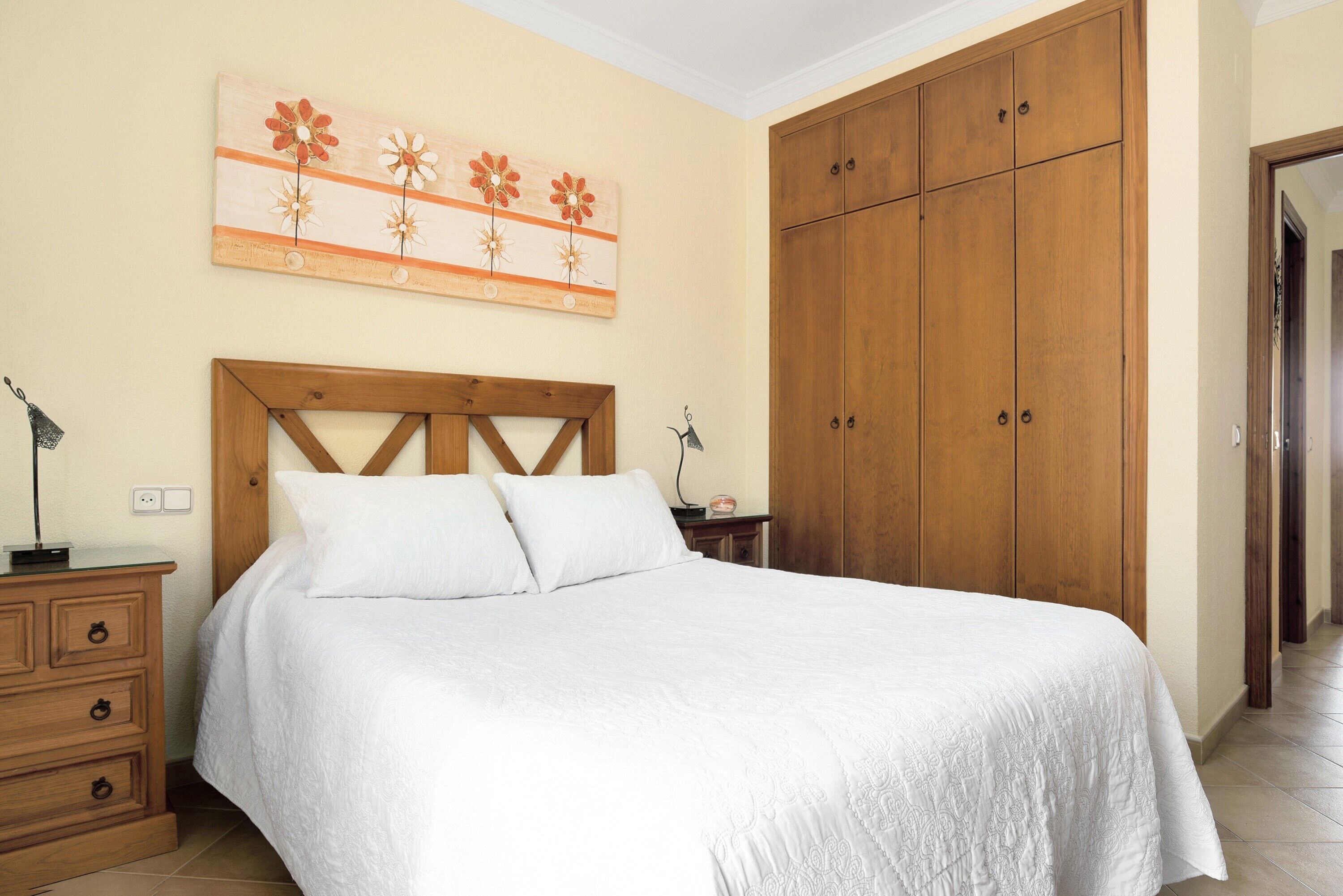 Una camera da letto con una struttura letto in legno, un comodino, una cassettiera e un armadio.