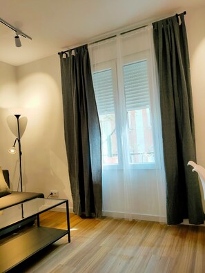 A room with a bed, a desk, a lamp, and a window with curtains.