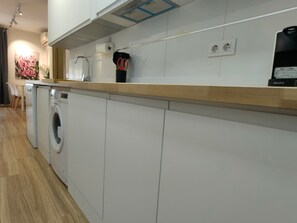 A modern kitchen with a washing machine, a countertop, and a power outlet.