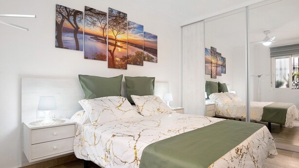 A bedroom with a large bed, a nightstand, a mirror, and wall art. - Studio Apartment "Loft Centro Historico Barbate" close to the Sea with Wi-Fi (Barbate)
