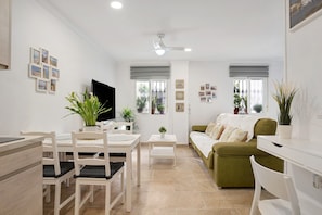 Ein modernes Wohnzimmer mit einer Couch, einem Esstisch, Stühlen und einem Fernseher.