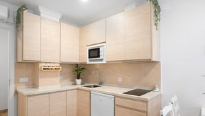 A compact kitchen with light wood cabinets, a built-in microwave, a dishwasher, and a sink. - Studio Apartment "Loft Centro Historico Barbate" close to the Sea with Wi-Fi (Barbate)