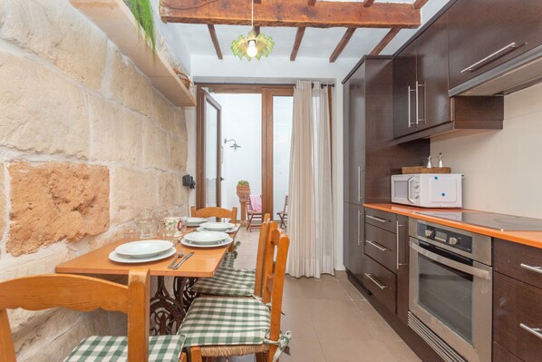 A kitchen with a dining table set for four, a microwave, and a built-in oven.
