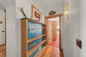 A hallway with wooden shelving, a framed picture, and a door leading to another room.