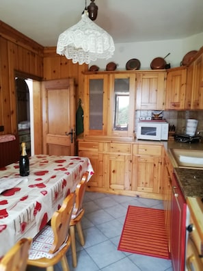 Une cuisine en bois avec une table à manger, des chaises, un four à micro-ondes et des placards.