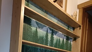 Ein Holzbeschilderungskasten mit Glasscheiben, auf denen jeweils verschiedene Waldszenen mit Rehen abgebildet sind.