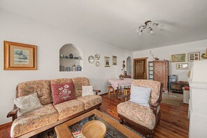 A cozy living room with patterned sofas, a coffee table, and a dining area with a table and chairs.