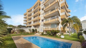 Un immeuble résidentiel à plusieurs étages, avec une piscine en premier plan.