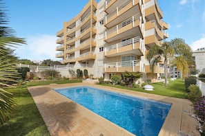 A multi-story residential building with a swimming pool in the foreground.