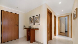 Un couloir avec une porte en bois, un bureau avec une bougie et des tableaux encadrés accrochés au mur.