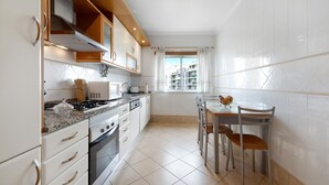 Une cuisine moderne avec des meubles blancs, une cuisinière et un coin repas comprenant une table et des chaises.