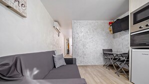Une cuisine moderne avec un pare-feu en marbre, un canapé gris et un coin repas comprenant une table et des chaises.
