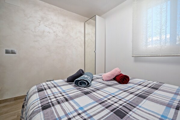 Une chambre à coucher avec un lit, un miroir et une fenêtre.
