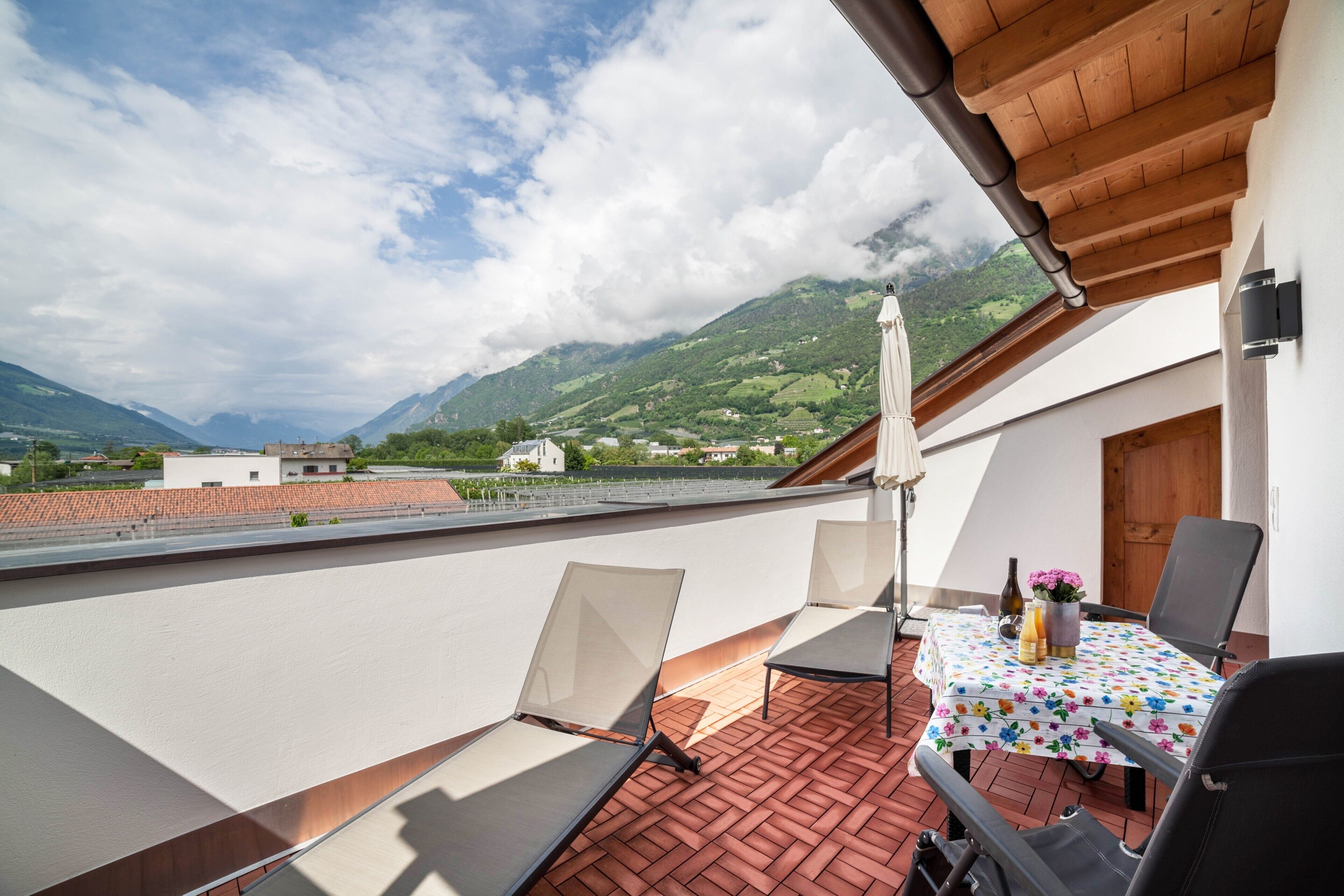 Une terrasse avec une table, des chaises et une vue sur les montagnes.