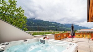 A hot tub on a wooden deck with a mountain view. - Apartment "Sagschneiderhof Golden Delicious" with Mountain View, Whirlpool & Wi-Fi (Plaus)