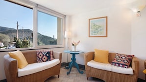 A room with two wicker sofas, a small blue table, a lamp, and a framed picture on the wall.