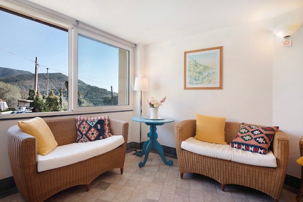 A room with two wicker sofas, a small blue table, a lamp, and a framed picture on the wall.