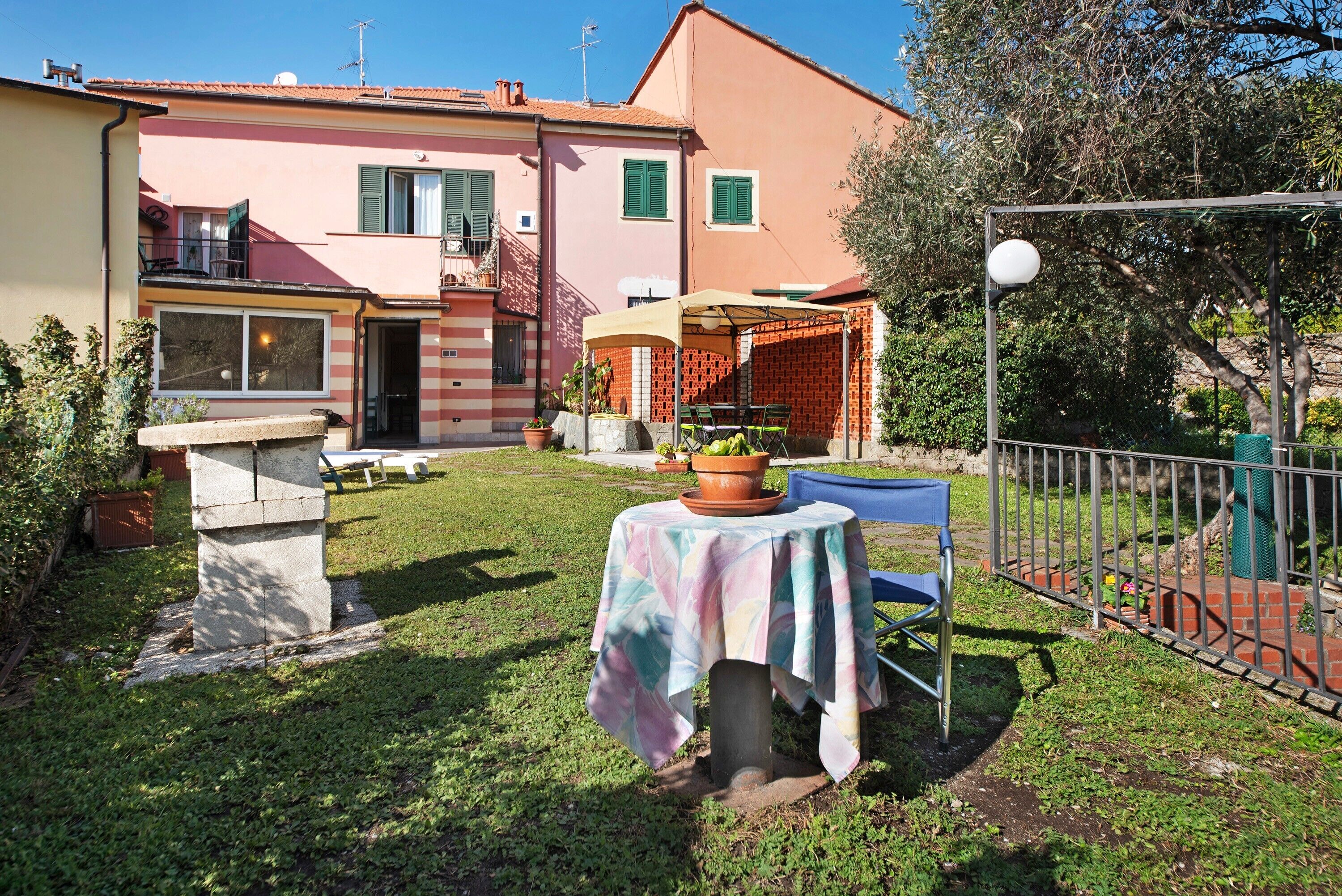 A residential property with a patio, a table with a tablecloth, a chair, and a small garden area.