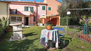 A residential property with a patio, a table with a tablecloth, a chair, and a small garden area.