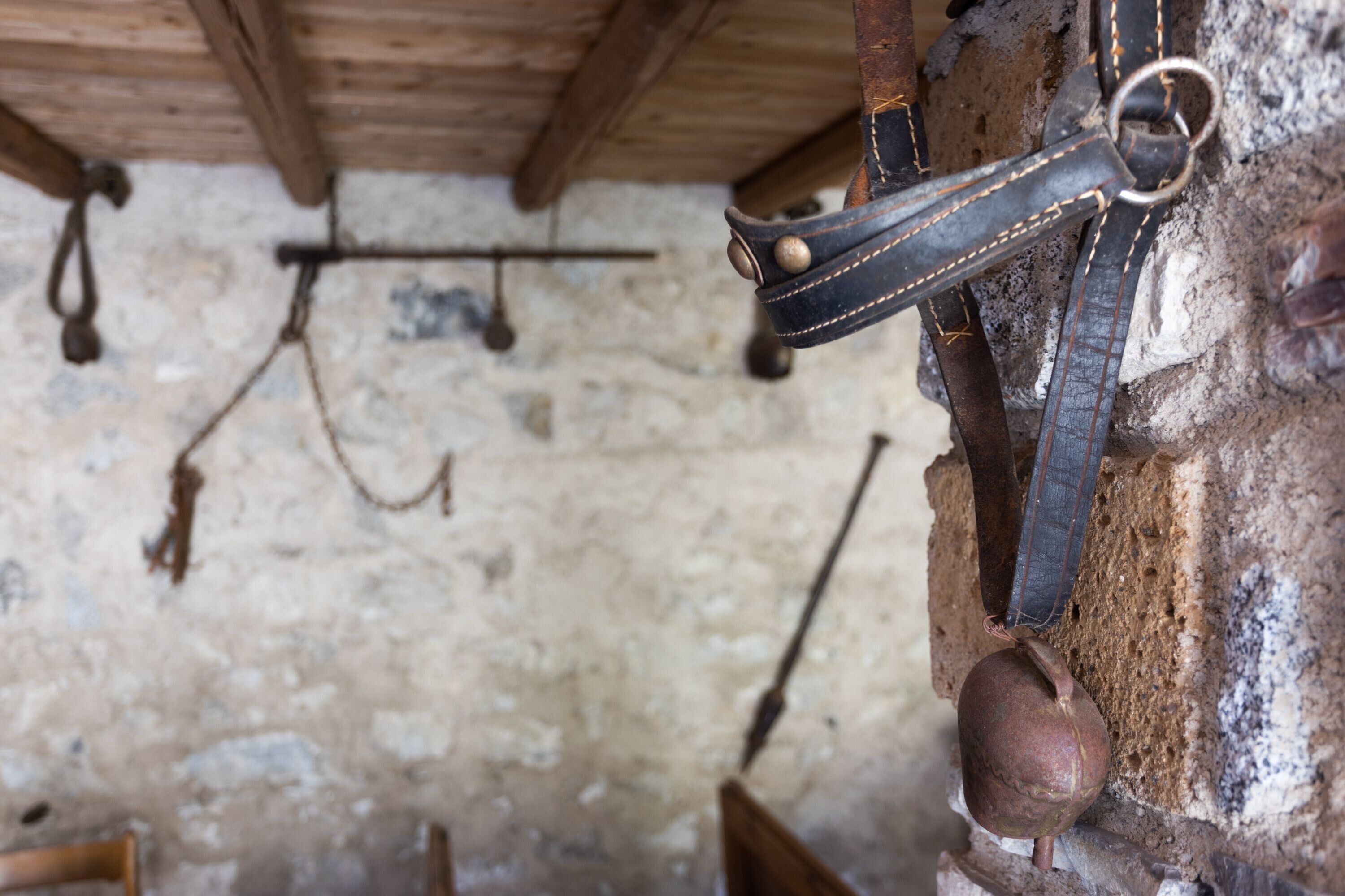 Un intérieur rustique avec des murs en briques apparentes, des poutres en bois et des outils suspendus.