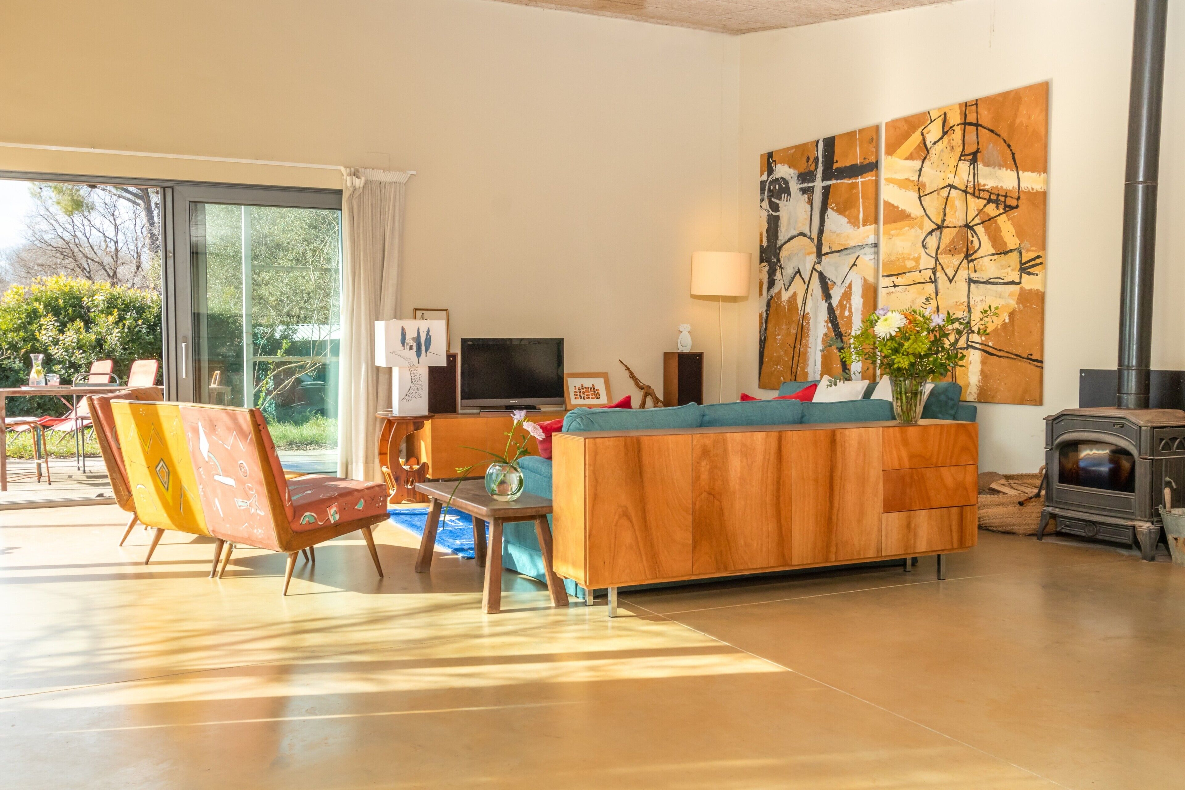 Ein Wohnzimmer mit Sofa, Sessel, Fernseher, Kamin und einem großen abstrakten Gemälde.