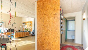 Ein modernes Wohnzimmer mit einer Wand in Holzoptik, einem roten Teppich und einer Küche im Hintergrund.
