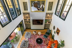A spacious living area with a fireplace, seating, and large windows. - Tropical Paradise with Heated Pool - Minutes to FQ (New Orleans)