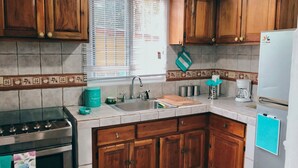 Una cucina con mobili in legno, un lavello in acciaio inox, un fornello e un frigorifero.
