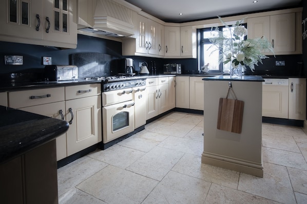 Functional kitchen with a central island, white cabinetry, and stainless steel range hood.