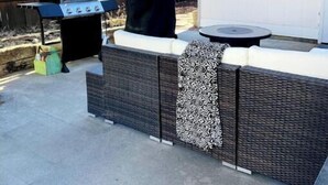 An outdoor patio with a grill, seating area, and a satellite dish.
