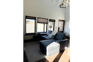 Relax in this stylish living room with a sofa and ottoman, facing a window with a desert view.