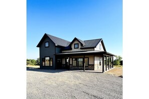 Situated on a gravel driveway, this two-story house features a symmetrical design with a covered porch area.