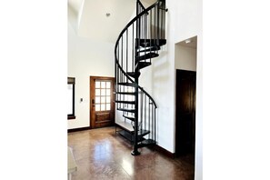 Stunning room with a high ceiling, polished floor, and a spiral staircase leading to an upper level.
