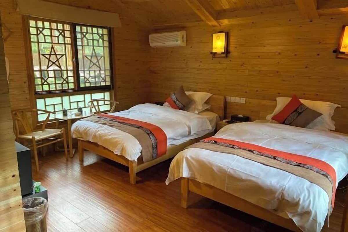 A wooden cabin with two beds, a window with a star pattern, and a small table.