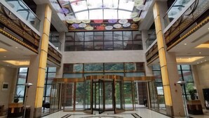 A spacious lobby with a glass ceiling, a revolving door, and a central decorative element. - Heizhugou Midou Hotel (Ebian)